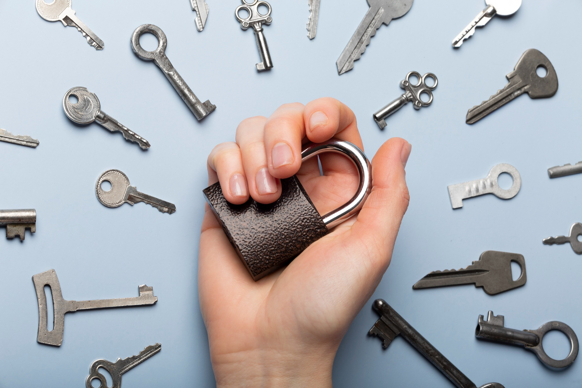 A hand holding a lock with a lot of keys around the hand in a circle